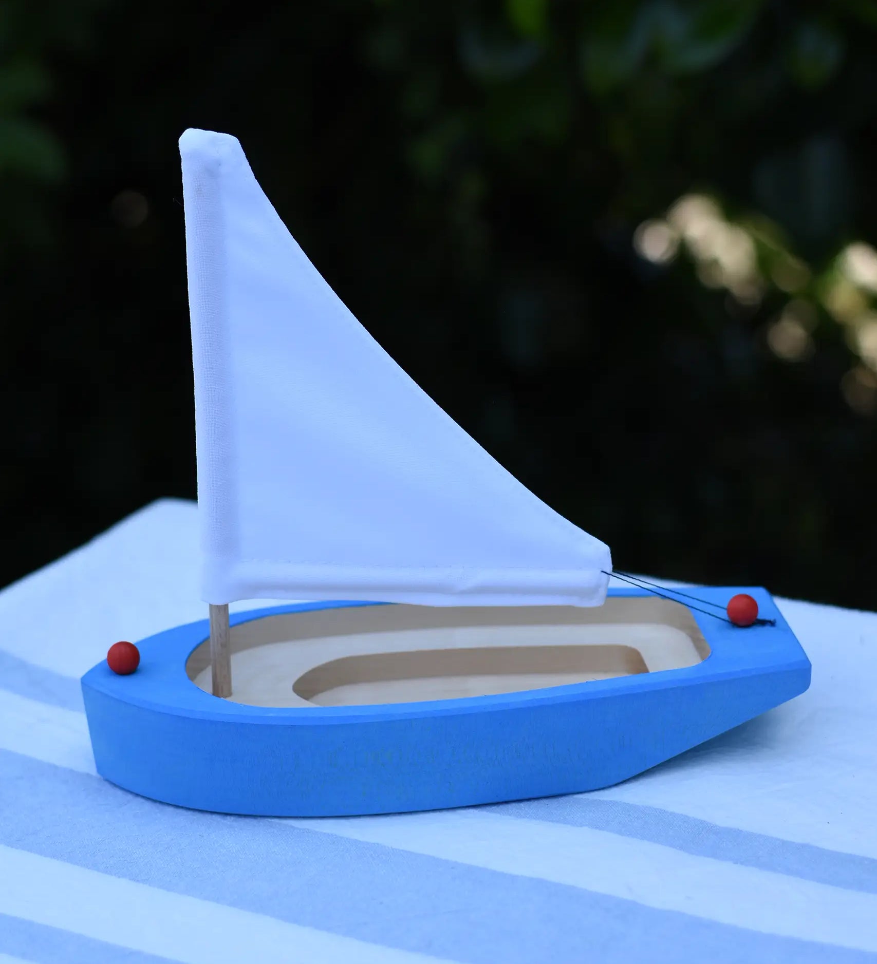 Glückskäfer wooden sailing ship in blue placed on a table outdoors.