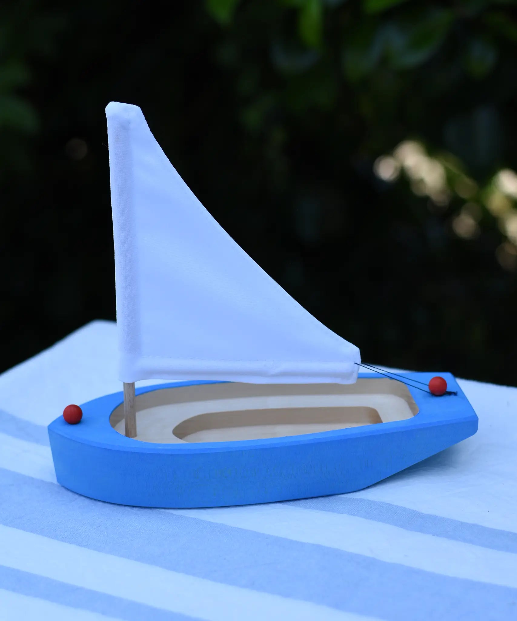 Glückskäfer wooden sailing ship in blue placed on a table outdoors.