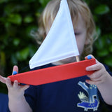 Child holding the Glückskäfer wooden sailing ship in red.