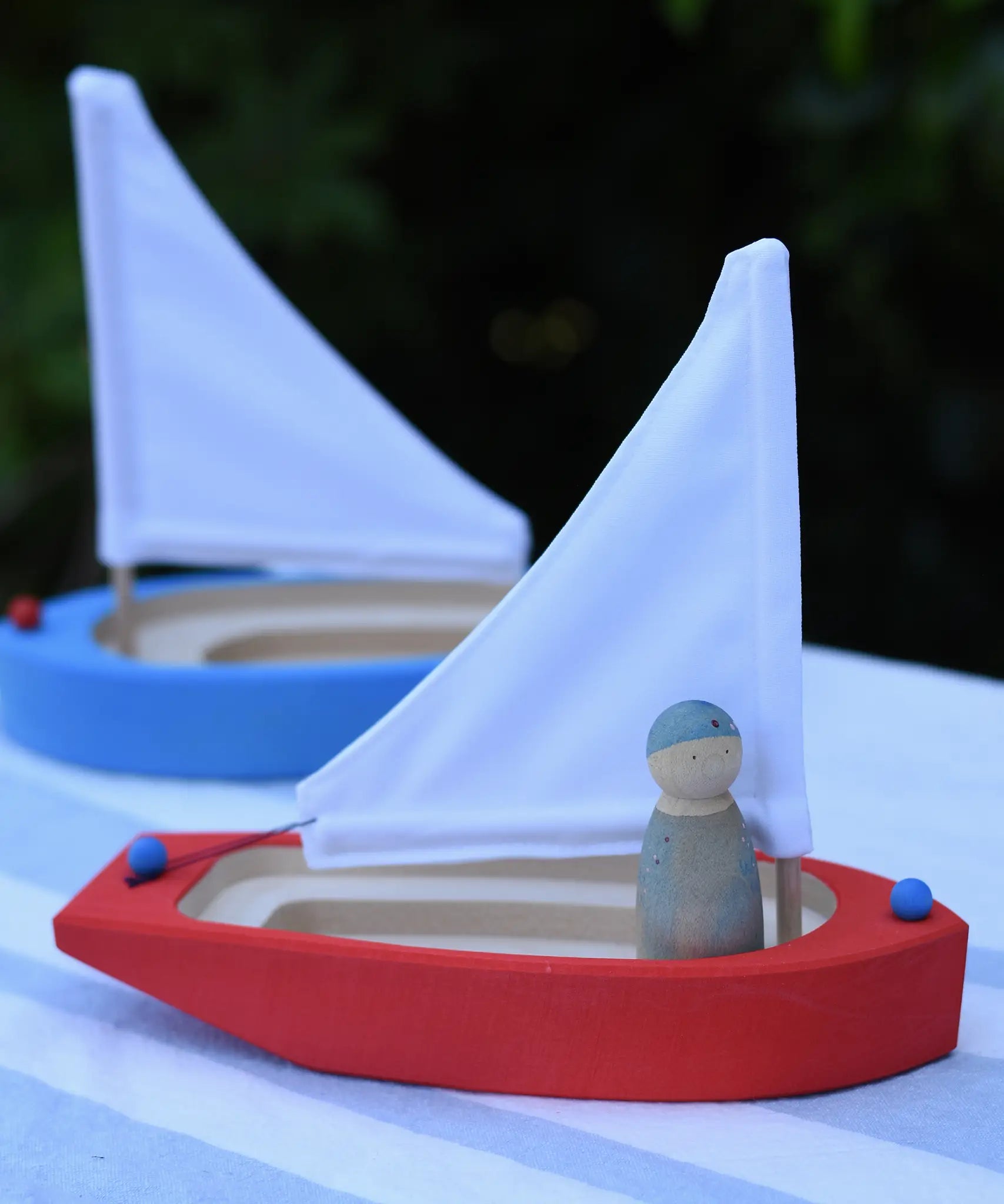  Glückskäfer wooden sailing ship in red with a blue Grapat Nin placed inside with a blue boat in the background.