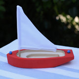 Glückskäfer wooden sailing ship in red placed on a table outdoors. 