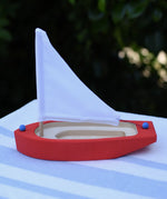 Glückskäfer wooden sailing ship in red placed on a table outdoors. 