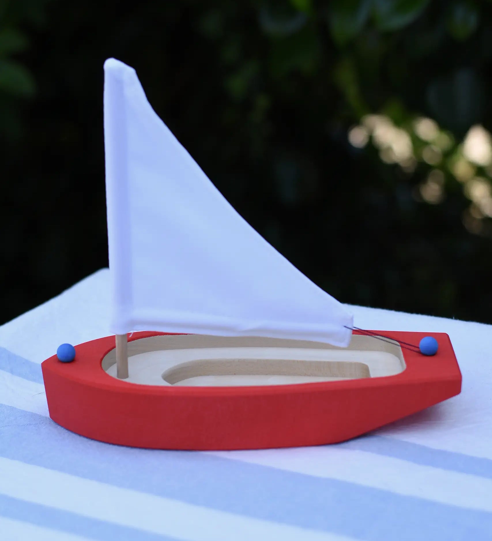 Glückskäfer wooden sailing ship in red placed on a table outdoors. 