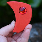 Red pieces from the Glückskäfer sparkling swirl wooden spinning toy in an adult's hand.
