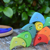Pieces from the Glückskäfer sparkling swirl wooden spinning toy stacked up on a wooden surface. 