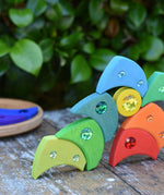 Pieces from the Glückskäfer sparkling swirl wooden spinning toy stacked up on a wooden surface. 