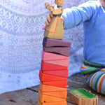 The segments from the Glückskäfer Yellow Sunray Arch all stacked up, a young child is placing an Ostheimer figure on the top.