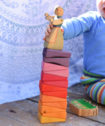 The segments from the Glückskäfer Yellow Sunray Arch all stacked up, a young child is placing an Ostheimer figure on the top.
