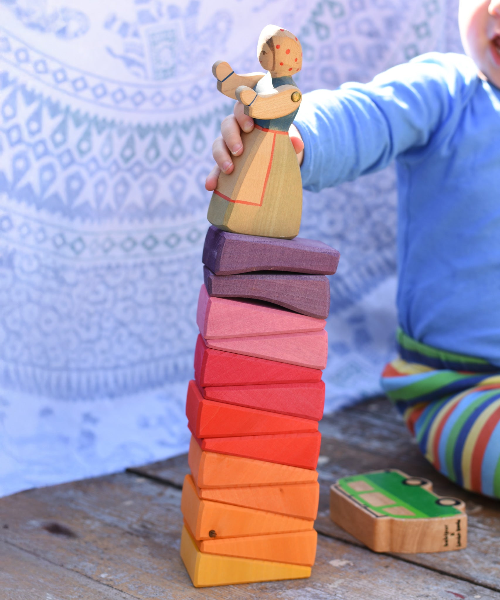 The segments from the Glückskäfer Yellow Sunray Arch all stacked up, a young child is placing an Ostheimer figure on the top.