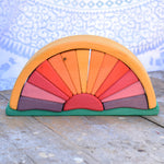 A Glückskäfer Yellow Sunray Arch placed on a wooden surface in front of a patterned cloth. 