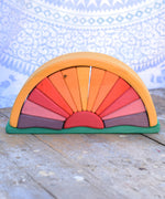 A Glückskäfer Yellow Sunray Arch placed on a wooden surface in front of a patterned cloth. 