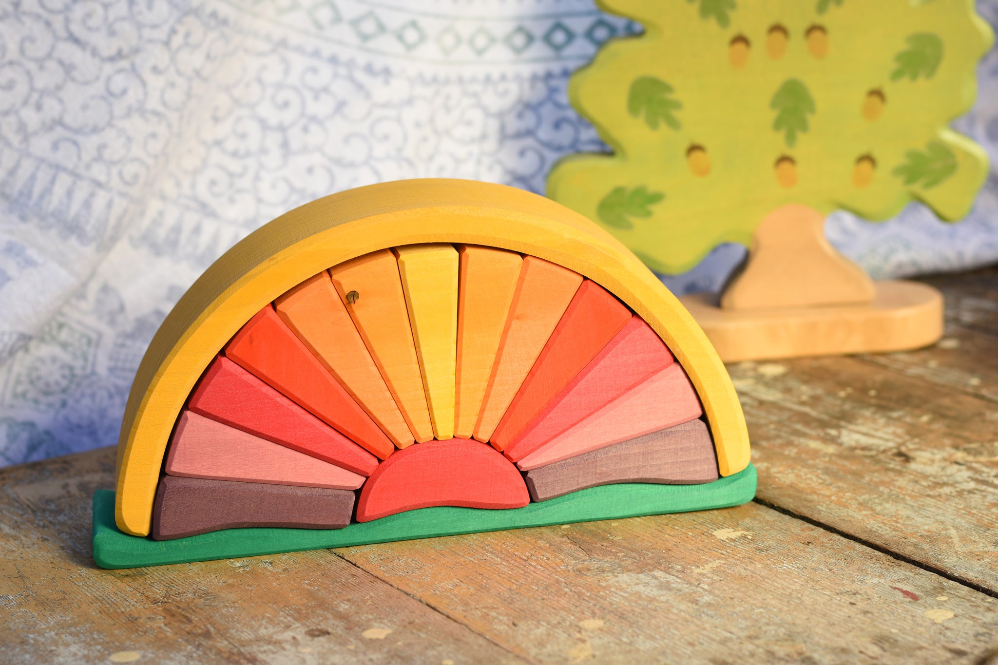 The Glückskäfer Yellow Sunray Arch placed on a wooden surface with a Holztiger oak tree figure in the background. 