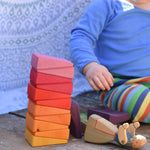 A small child playing with the Glückskäfer Yellow Sunray Arch, stacking the pieces on top of each other.