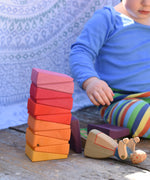 A small child playing with the Glückskäfer Yellow Sunray Arch, stacking the pieces on top of each other.