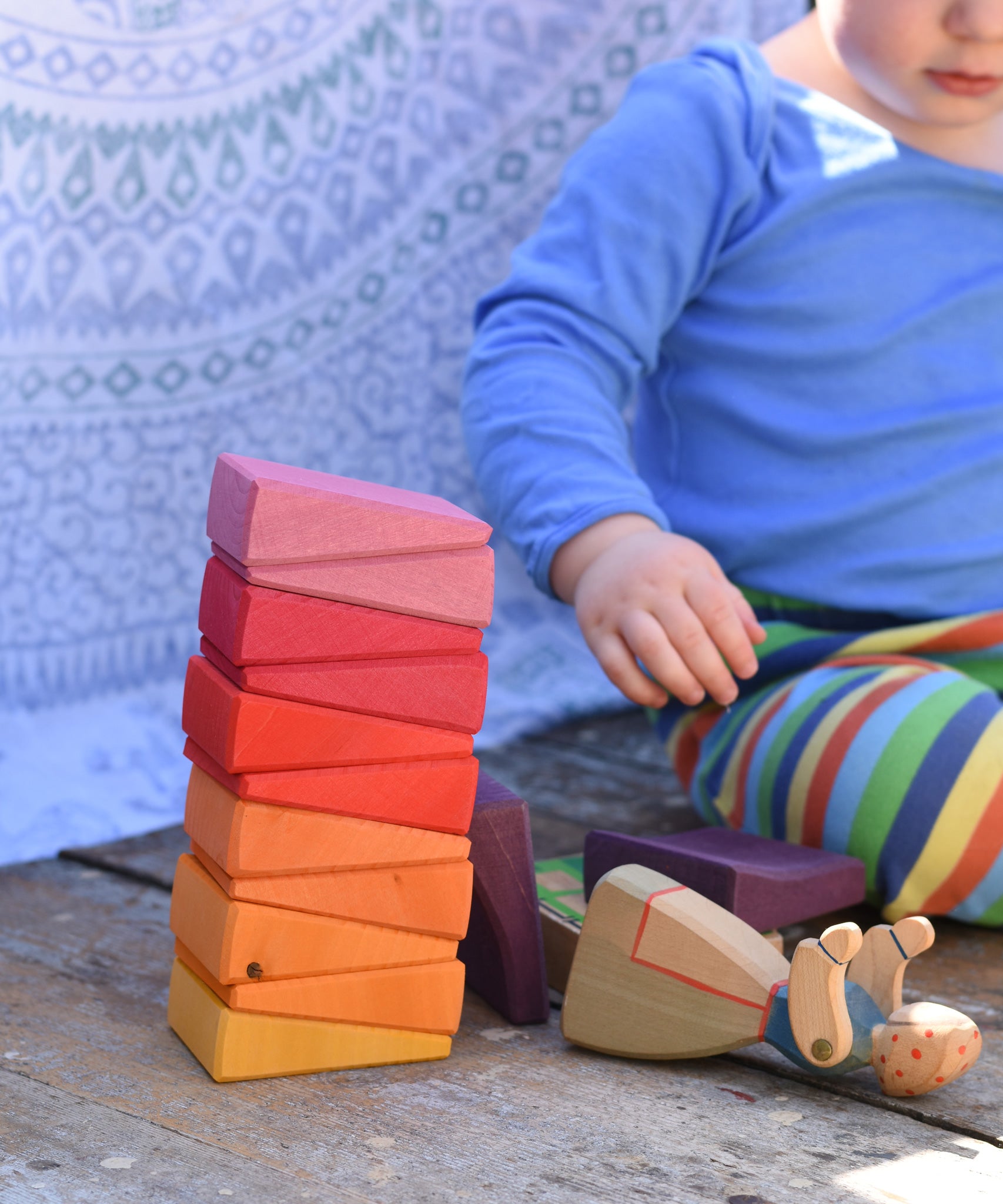 A small child playing with the Glückskäfer Yellow Sunray Arch, stacking the pieces on top of each other.