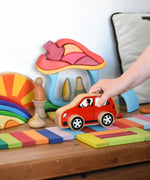 A wooden Lanka Kade car being driven over a rainbow coloured read created using the Glückskäfer 60 Tower Building Slats.