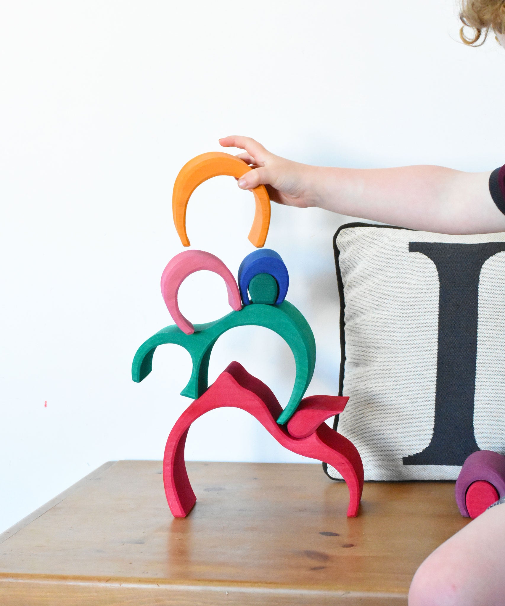 A child stacking pieces of the Glückskäfer Gable House wooden toy on top of each other 