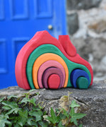 The Glückskäfer Gable House 9 Piece Wooden Toy placed on a stone wall outdoors. 
