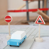 Gluckskafer miniature railway crossing wooden traffic sign next to a playroad and Candylab car on top and parking garage in the background