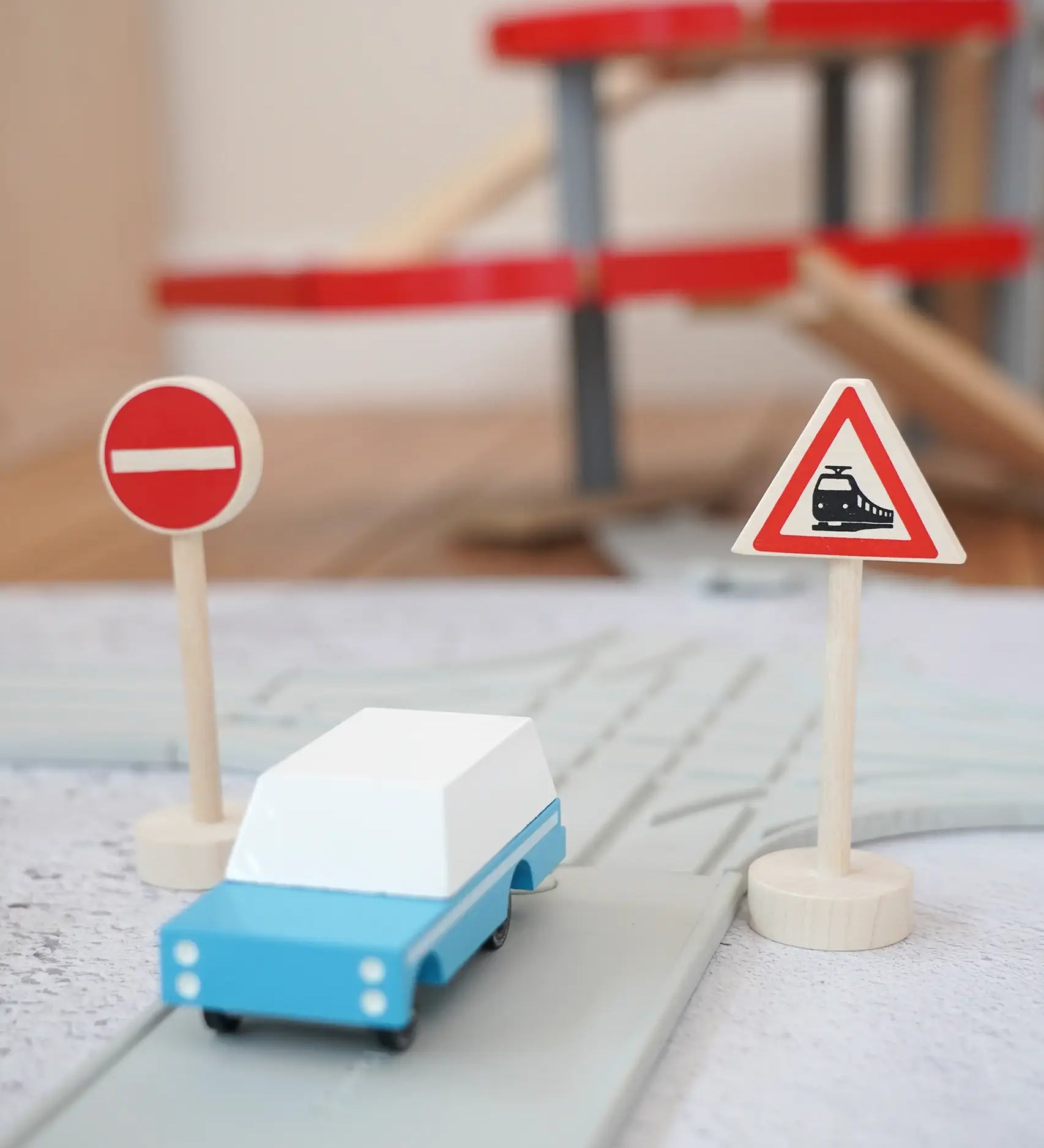 Gluckskafer miniature railway crossing wooden traffic sign next to a playroad and Candylab car on top and parking garage in the background