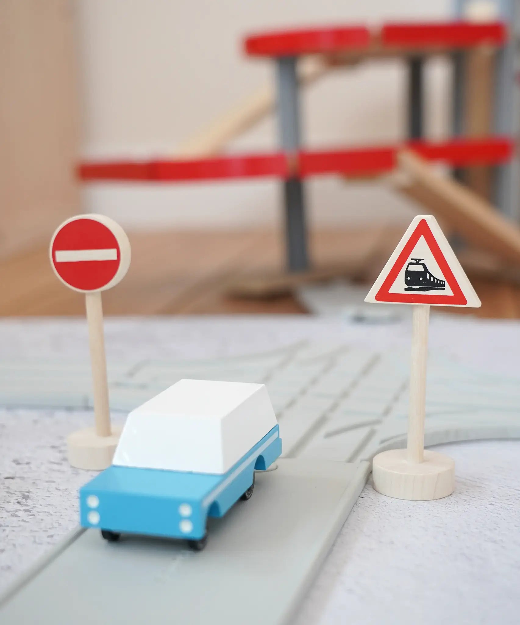 Gluckskafer miniature railway crossing wooden traffic sign next to a playroad and Candylab car on top and parking garage in the background