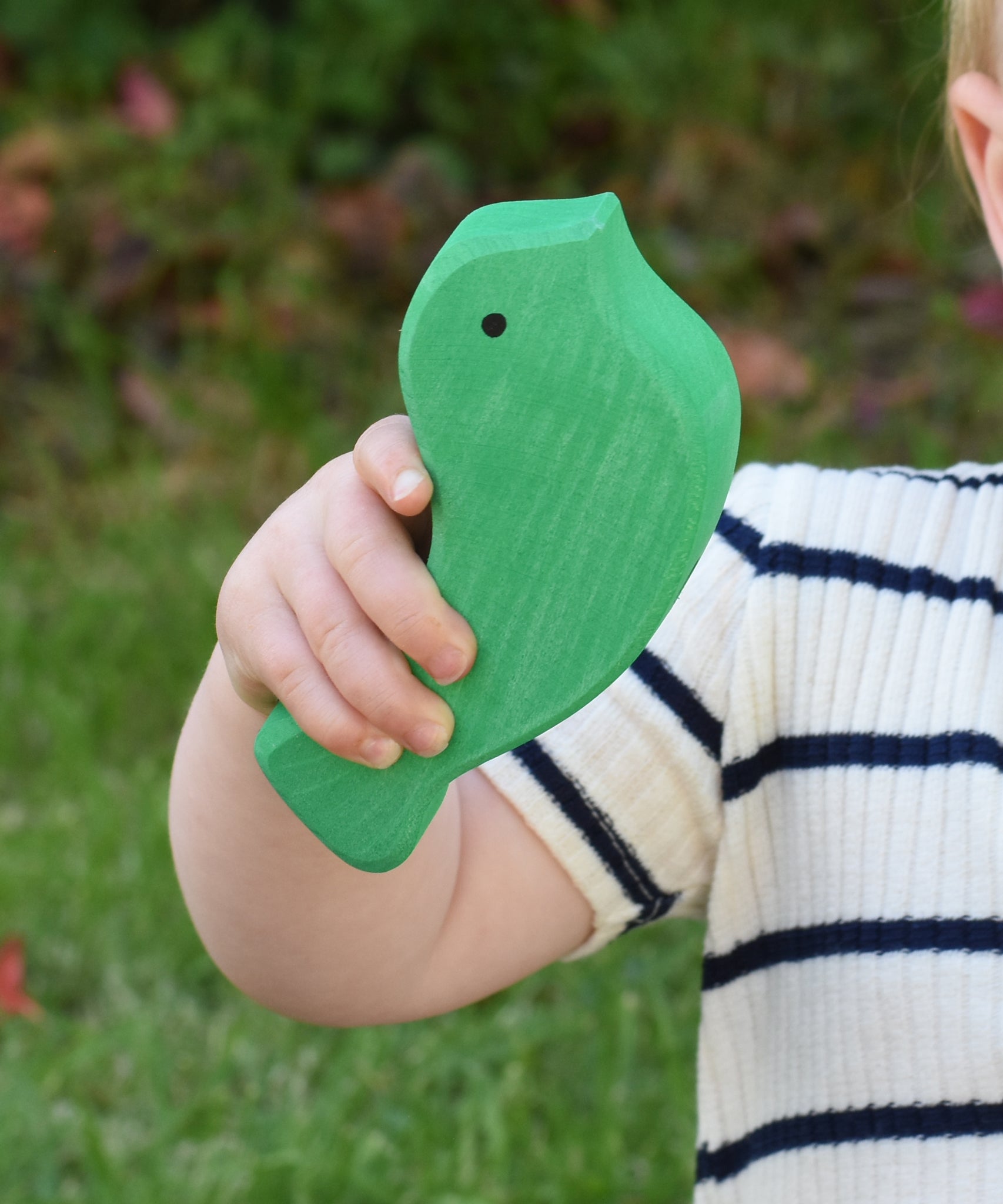 A close up of the green bird from the Glückskäfer Bird Stacker in a child's hand. 
