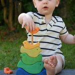 A child playing with the Glückskäfer Bird Stacker placing one of the orange coloured birds onto the stack. 
