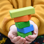 A close up of five different blocks from the Glückskäfer 29-Piece House Blocks in a child's hands.