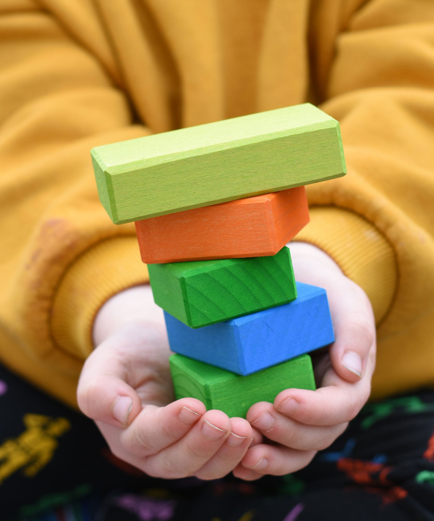 A close up of five different blocks from the Glückskäfer 29-Piece House Blocks in a child's hands.