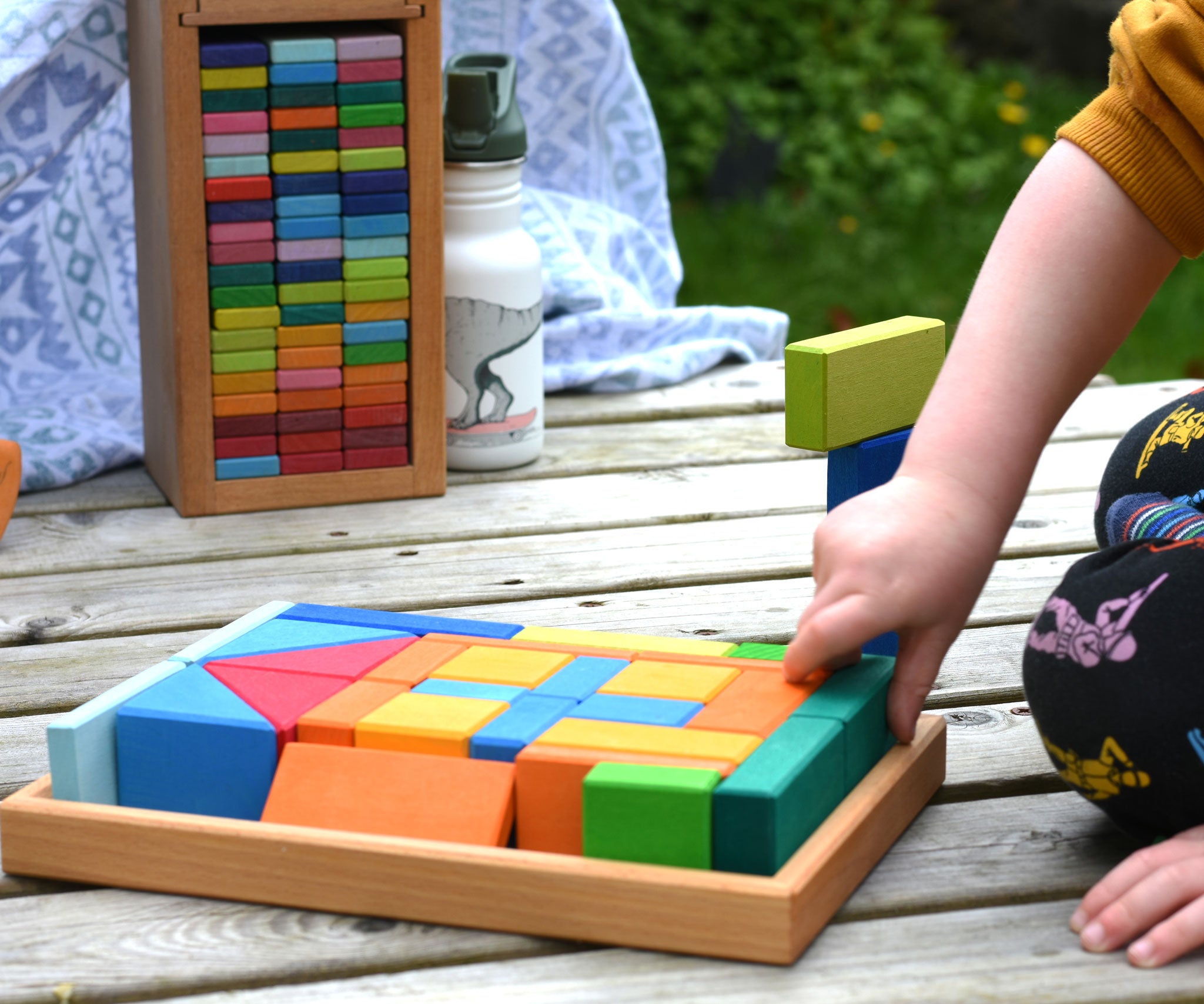 A child's hand taking pieces out of the tray from the Glückskäfer 29-Piece House Blocks set.