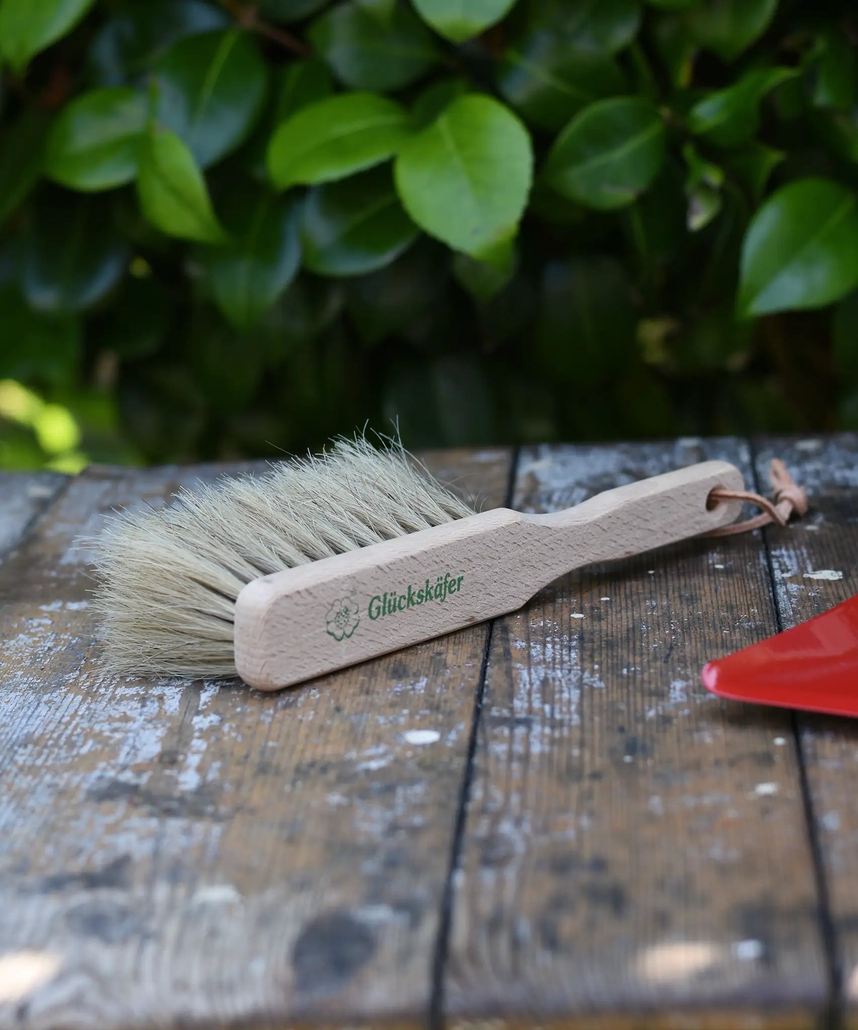 Glückskäfer wooden dust brush with natural horse hair bristles placed on a wooden surface.