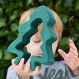 Child holding the large dark green pieces from the Glückskäfer 6-Piece Fir Tree wooden tree stacking toy.