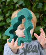 Child holding the large dark green pieces from the Glückskäfer 6-Piece Fir Tree wooden tree stacking toy.