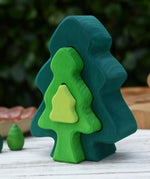 Glückskäfer 6-Piece Fir Tree wooden tree stacking toy with six nested tree shapes in shades of green placed on a wooden surface outdoors.