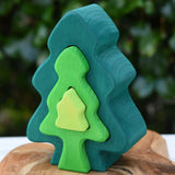 Glückskäfer 6-Piece Fir Tree wooden tree stacking toy with six nested tree shapes in shades of green placed on a wooden surface outdoors.