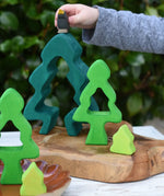Child playing with the Glückskäfer 6-Piece Fir Tree wooden tree stacking toy holding an Ostheimer blackbird in his hans.