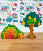The Glückskäfer Wooden Pear Tree Stacking Puzzle Toy shown next to a green arch house. 