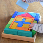 A close up of a young child's hand's taking blocks out of the Glückskäfer 29-Piece House Blocks set tray.