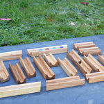 The pieces from the Glückskäfer 23 Piece Wooden Marble Track laid out onto a slate surface outdoors. 
