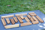 The pieces from the Glückskäfer 23 Piece Wooden Marble Track laid out onto a slate surface outdoors. 