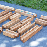 The pieces from the Glückskäfer 23 Piece Wooden Marble Track laid out onto a slate surface outdoors. 