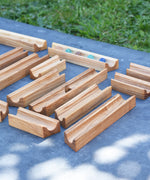 The pieces from the Glückskäfer 23 Piece Wooden Marble Track laid out onto a slate surface outdoors. 