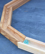 A glass marble placed on the Glückskäfer 23 Piece Wooden Marble Track laid out onto a slate surface outdoors. 