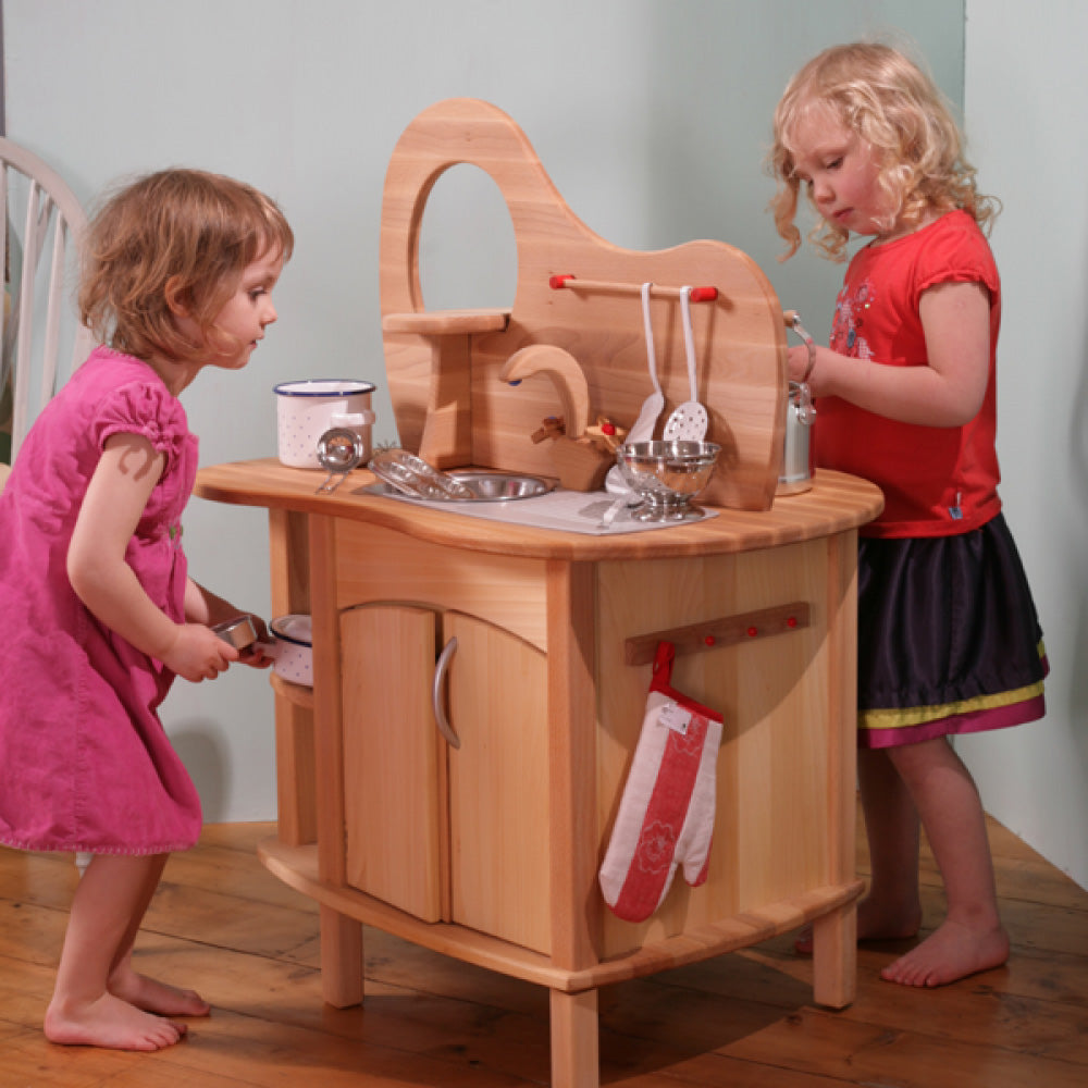 Two children preparing pretend food together at the Gluckskafer double-sided wooden play kitchen island.