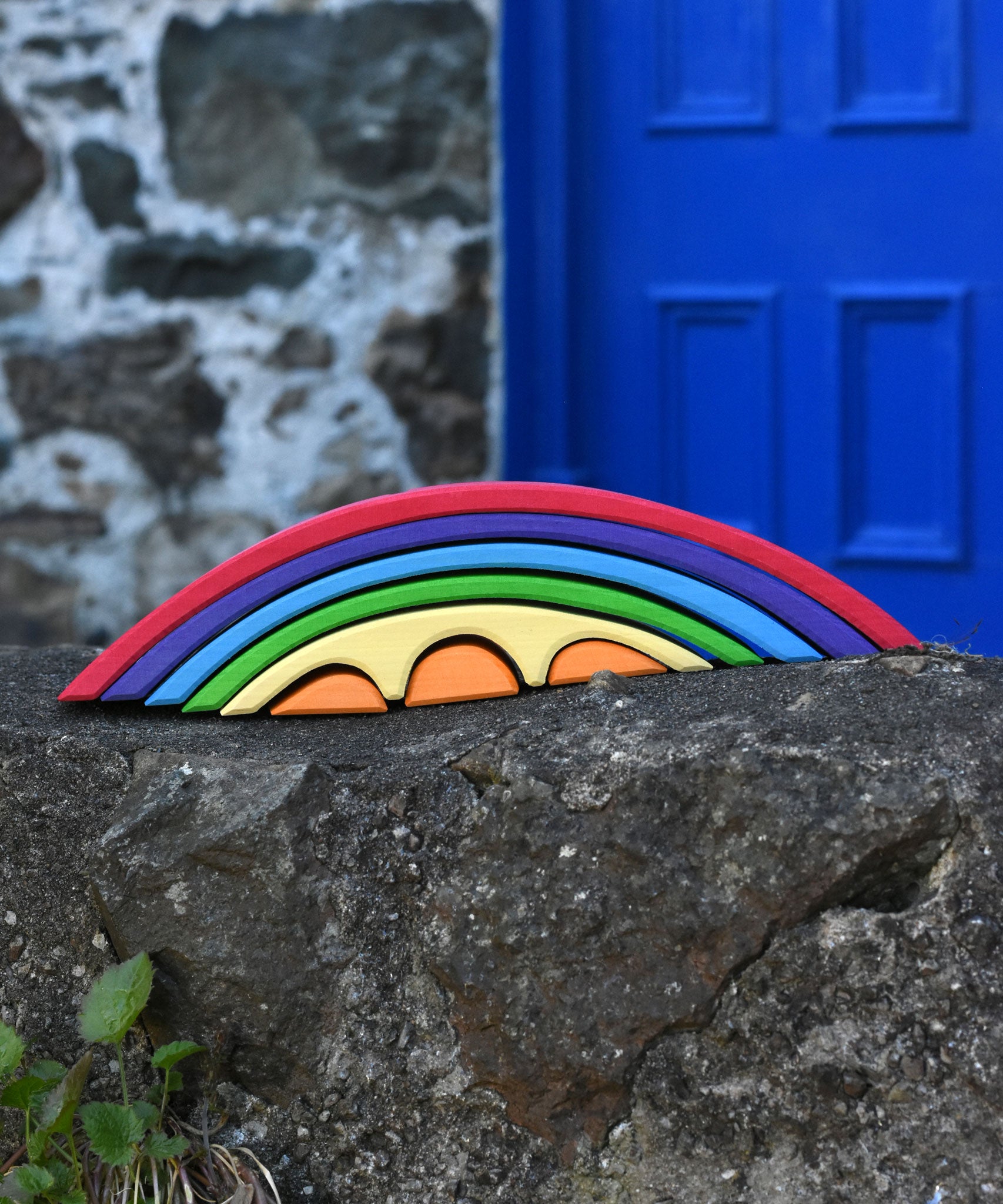 The Gluckskafer Rainbow Bridge placed on an uneven stone wall outdoors. 

