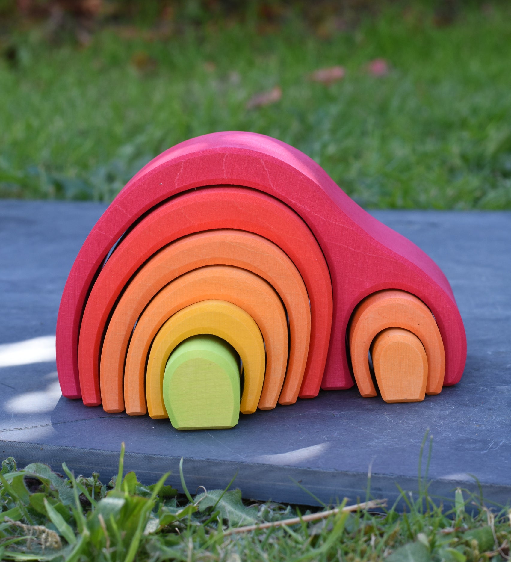 The Glückskäfer Red 8 Piece Arch House placed on a slate surface outdoors. 