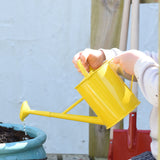 A child using the Glückskäfer Children's 1L yellow Metal Watering Can.
