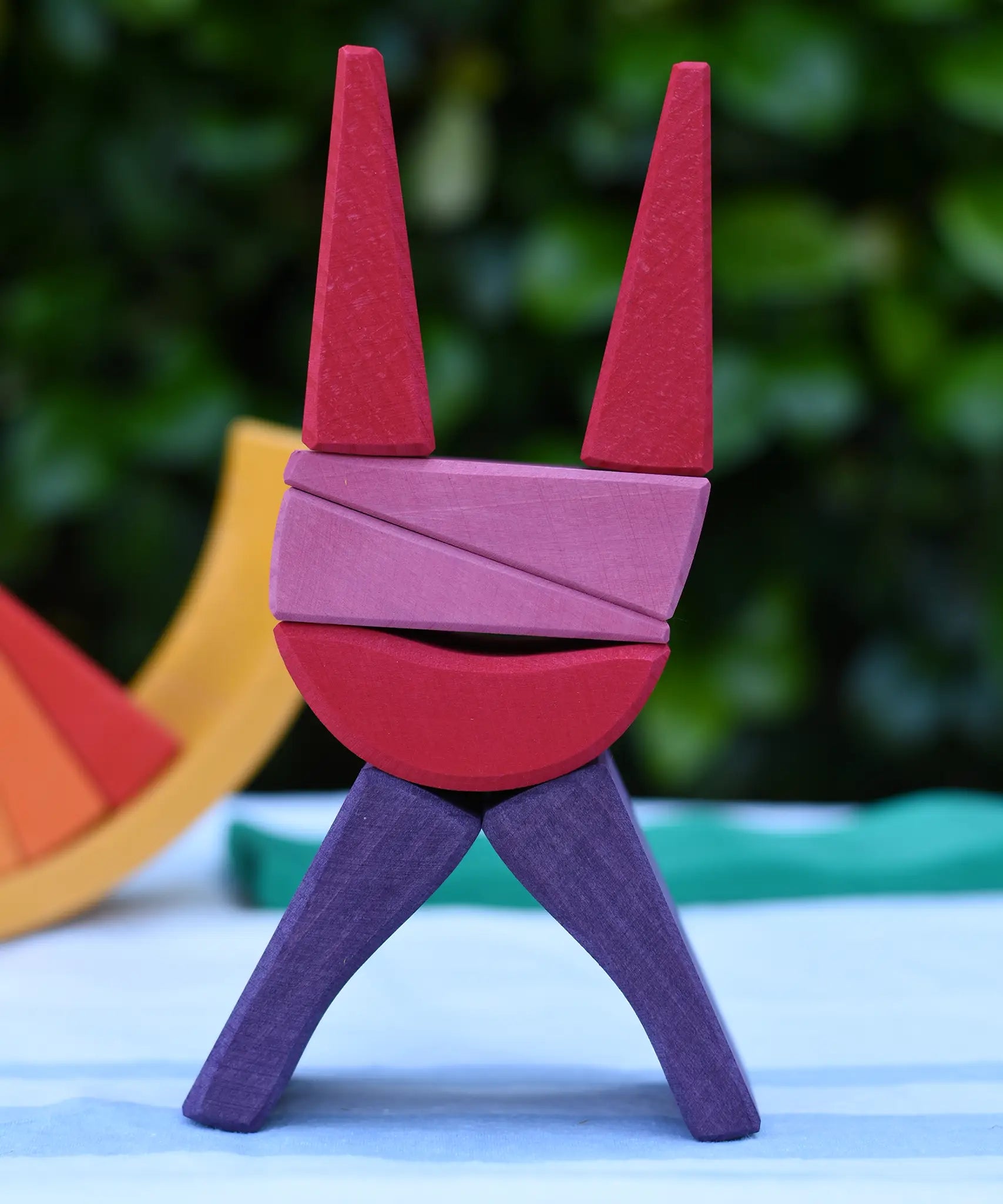 Blocks from the Glückskäfer wooden stacking sunray arch in yellow purple used to create a cat shaped stack.