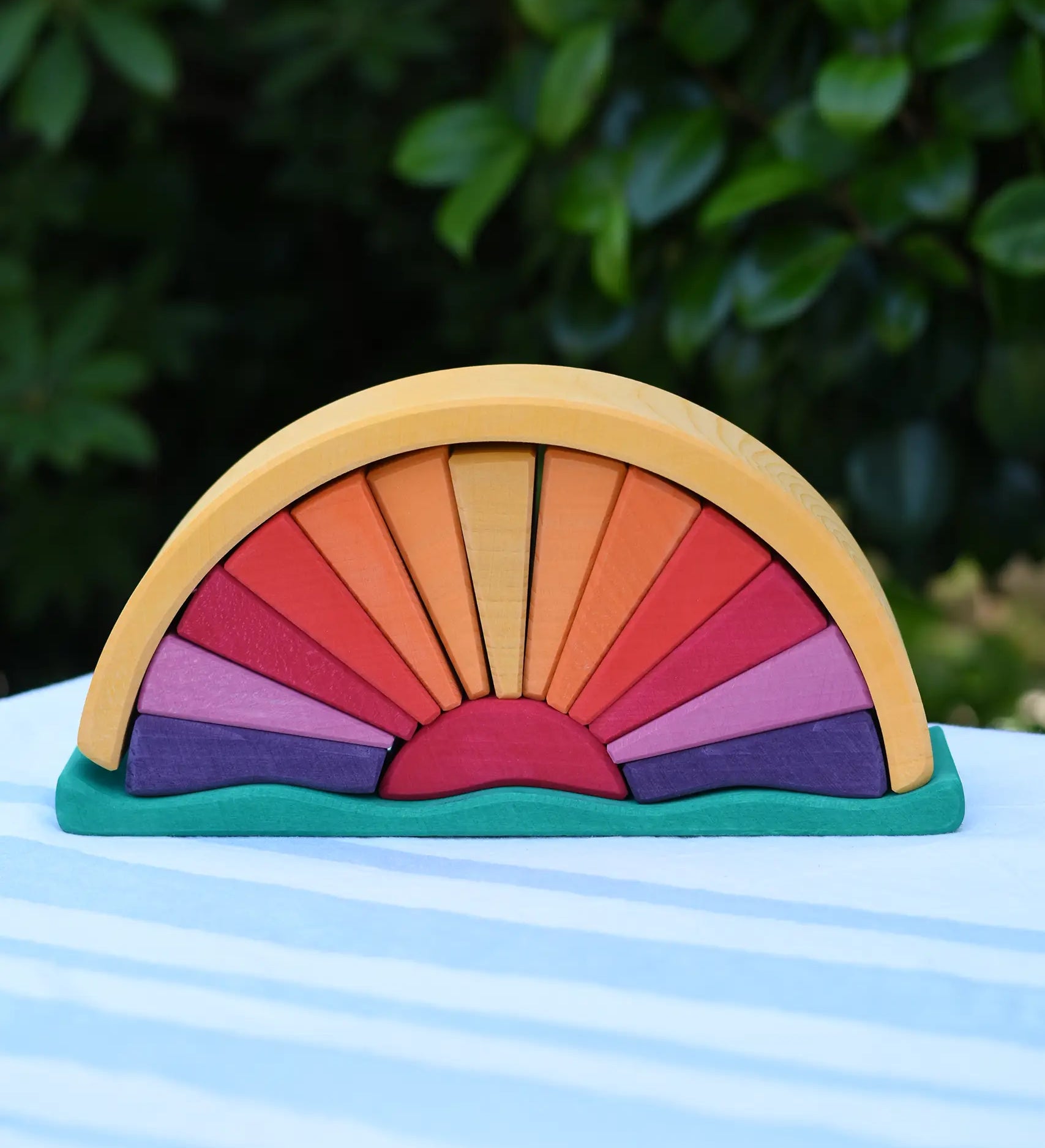 Glückskäfer wooden stacking sunray arch in yellow purple placed on a table outdoors. 