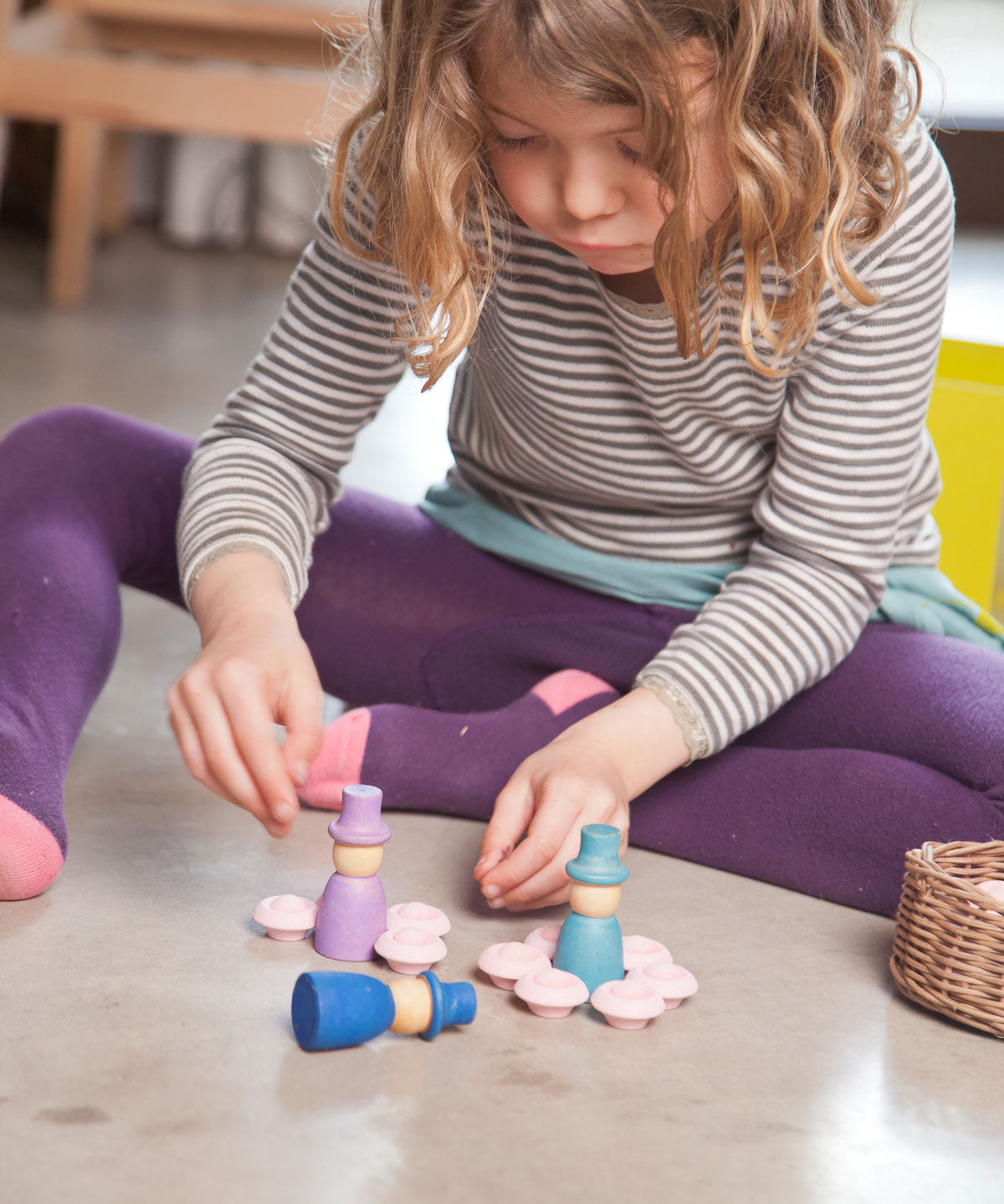 A close up of a child playing with the Grapat 12 Magos wooden peg dolls. These wooden toys are part of a wide range of open ended toys available at Babipur.  